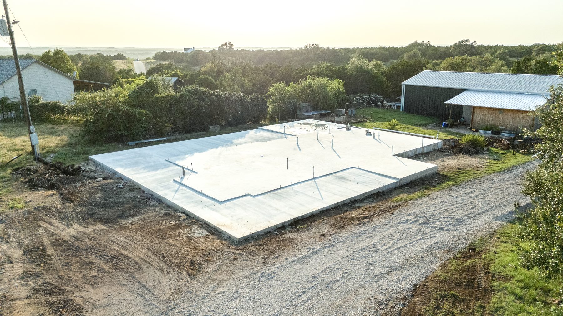 Aerial view of a freshly poured slab beside a metal shop building